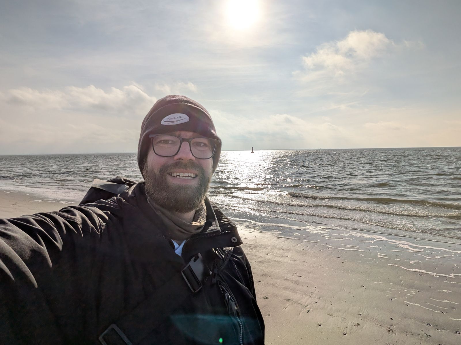 Marcus Aßhauer mit Mütze am Strand bei Gegenlicht